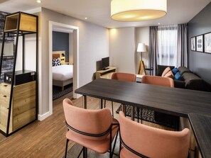 A hotel room with a bed, a desk, a dining table with chairs, a sofa, and a lamp. - Aparthotel Adagio London Sutton Point (Sutton)