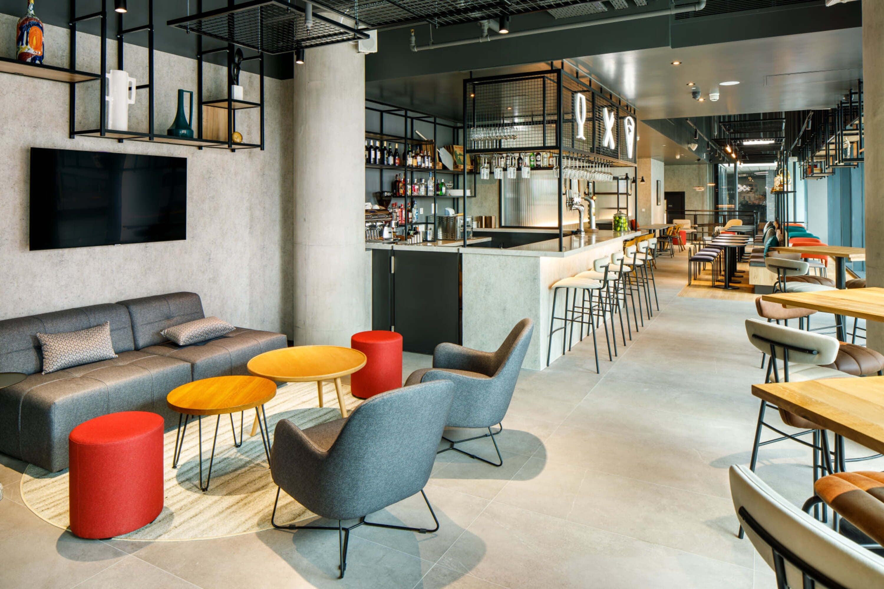 A modern interior with a bar area, seating arrangements, and a television.