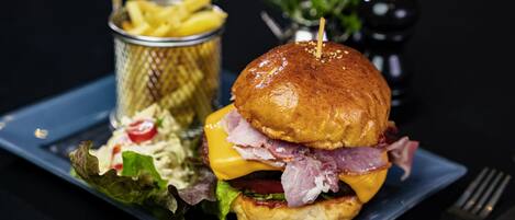 A sandwich with lettuce, tomato, cheese, and meat, accompanied by a side of fries and a small salad.