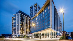 Ein modernes Hotel mit einer auffälligen Glasfassade, mehreren Etagen und einem gut beleuchteten Eingangsbereich.