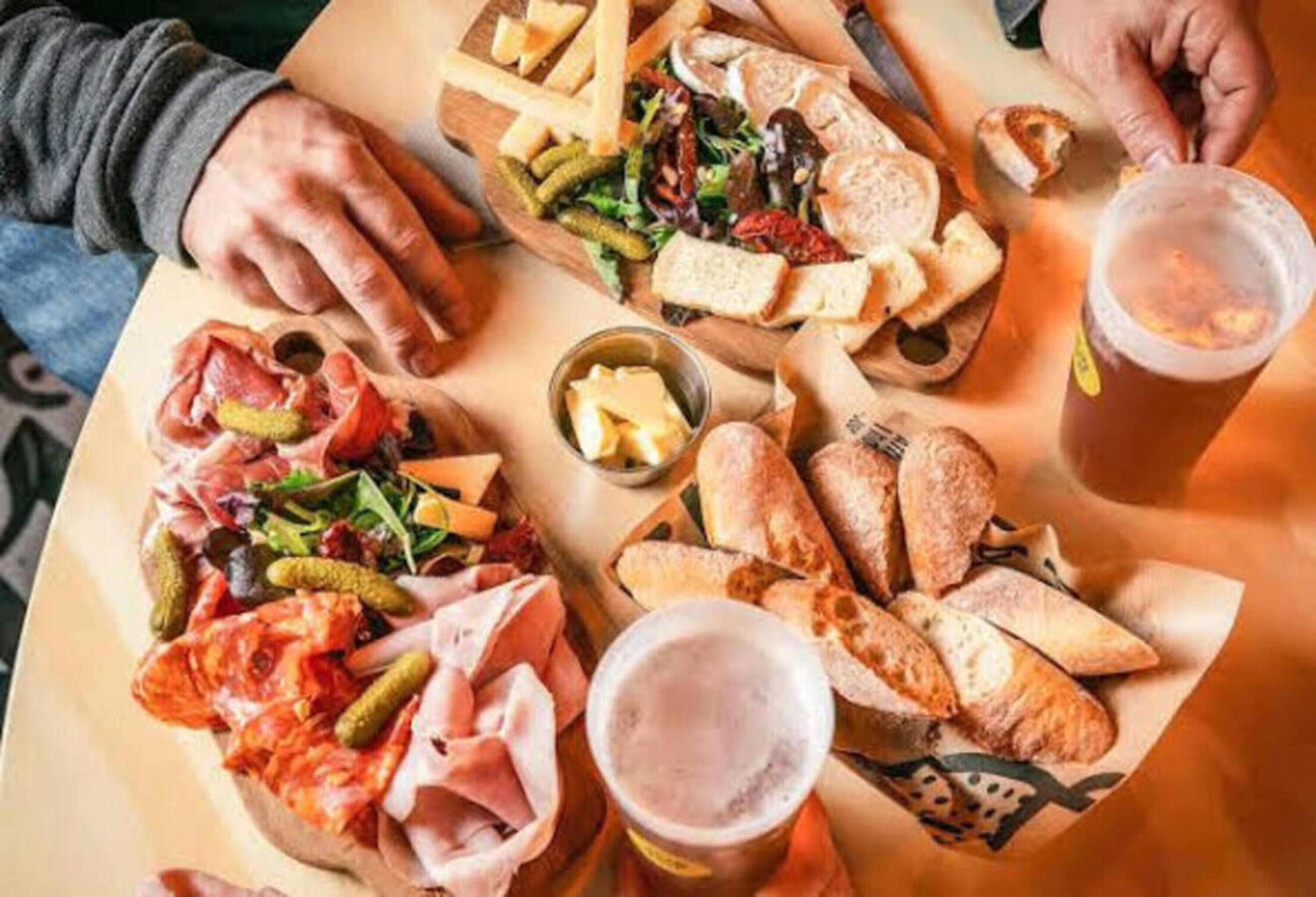 Een tafel met diverse etenswaren, zoals belegde broodjes, brood en drankjes.