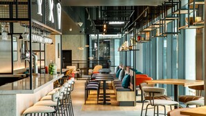Ein modernes Café mit Barhocker, hohen Tischen und einer Mischung aus Sesseln und Sofas.