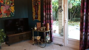 A living room with a TV, a coffee table, a cabinet, and a window with curtains.