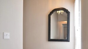 A hallway with a chandelier, a mirror, and a door.