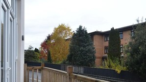 A balcony with a wooden fence, a white table, and a bench.