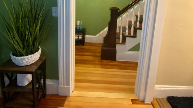 A staircase with a wooden finish, a green wall, and a painting above it.