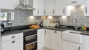 Een moderne keuken met witte kasten, een roestvrijstalen afzuigkap, een inbouwoven en een zwart aanrecht.