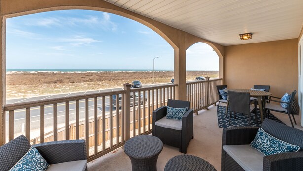 A covered outdoor area with wicker furniture, a view of the road, and a distant landscape.