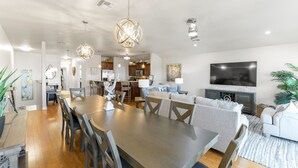 A spacious living area with a dining table, sofas, and a TV.