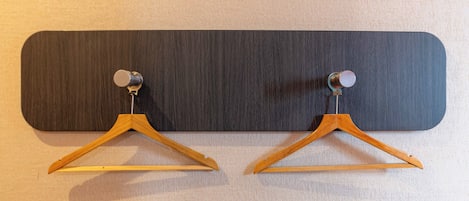 A wall-mounted wooden hanger with a metal hook, likely for hanging coats or bags.