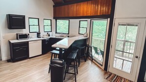 A modern kitchen with a wooden ceiling, large windows, and a dining area with bar stools. - The Cabin on Current River with Private Gravel Bar!! (Van Buren)