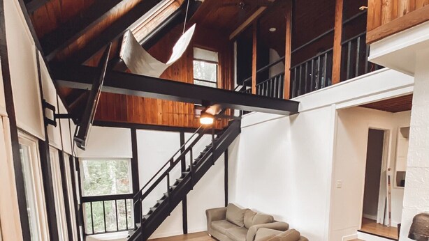 A spacious loft with a wooden floor, a staircase, a sofa, and a dining table. - The Cabin on Current River with Private Gravel Bar!! (Van Buren)