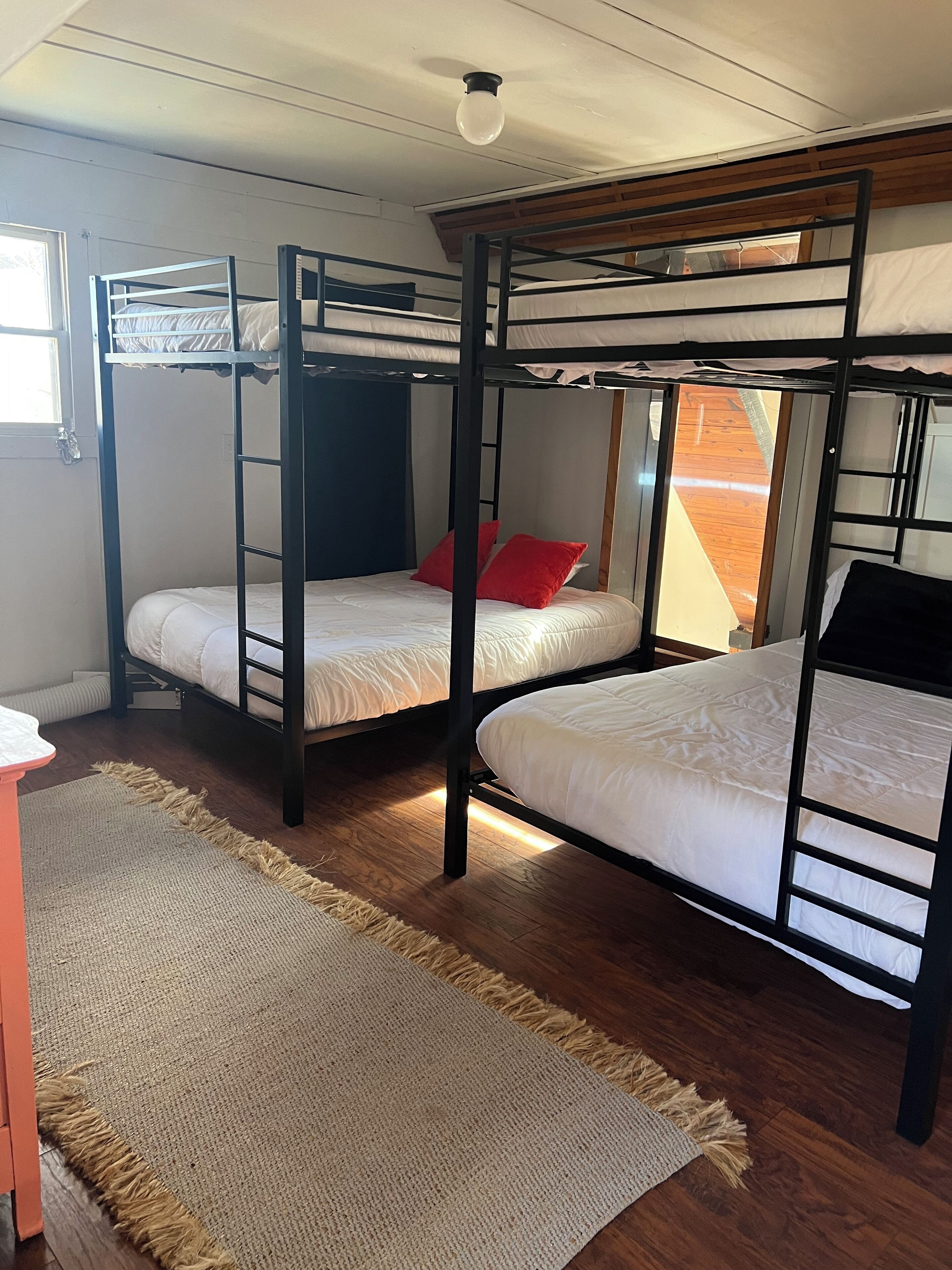 Een kamer met stapelbedden, een raam en een houten vloer.