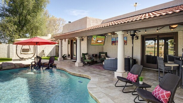 A pool area with a red umbrella, lounge chairs, and a pergola with string lights. - Quiet Desert Oasis on Golf Course w/ Heated Pool (Mesa)