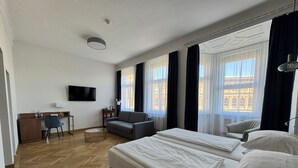 A hotel room with a large bed, a sofa, a desk, and a TV. - Hotel Secession an der Oper (Vienna)