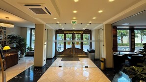 A hotel lobby with a marble floor, a reception desk, a staircase, and large windows offering a view of the outdoors. - Hotel Secession an der Oper (Vienna)