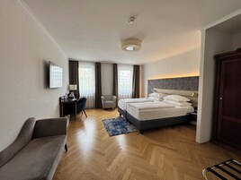 Quarto de hotel com cama, escrivaninha, cadeira e sofá.