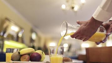 Una persona sirviendo jugo de naranja en un vaso.