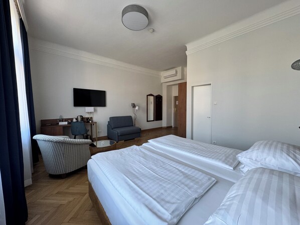 Una habitación de hotel con dos camas, un escritorio con silla, una televisión y un espejo.