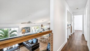 Ampla sala de estar com um banco de madeira, um sofá e uma mesa de jantar. Área de cozinha visível, com micro-ondas e pia.