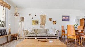 A living room with a wooden coffee table, striped sofa, and a dining area with wooden chairs and a table.