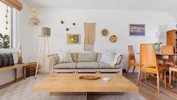 Una sala de estar con una mesa de centro de madera, sofá a rayas y un comedor con sillas y mesa de madera.