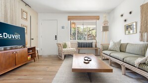 A living room with a television, sofa, coffee table, and a view of the outdoors.