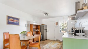 A modern kitchen with wooden chairs, a dining table, a refrigerator, and a microwave.