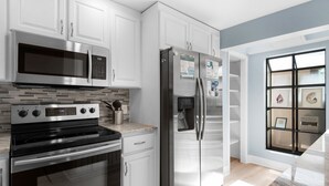 A modern kitchen with white cabinets, stainless steel appliances, and a tiled backsplash. - Golf Cart! | Lakefront Villa at Sandestin – On The Rocks ☀️ (Destin)