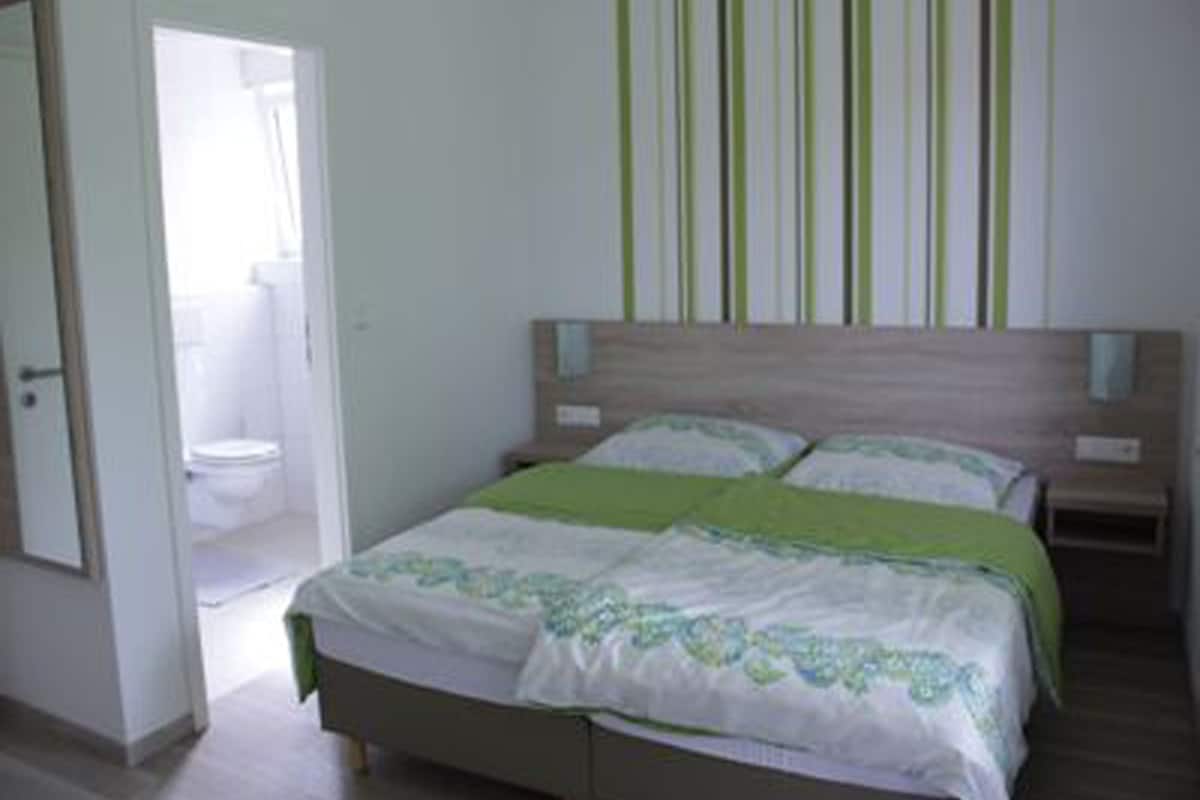 A bedroom with a bed, a nightstand, and a wall with vertical stripes.
