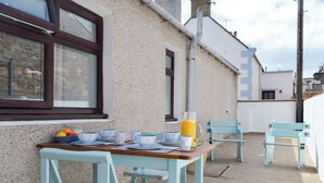 A table set with bowls and a pitcher of orange juice, two chairs, and a window with a stone wall. - Three Creeks Cottage (Portknockie)