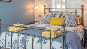 A bed with a metal frame, floral bedding, and two bedside lamps. - Three Creeks Cottage (Portknockie)