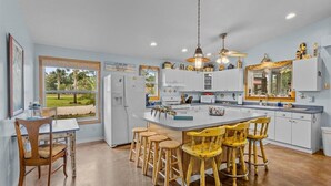 A kitchen with a central island, bar stools, and a view of the outdoors. - Cypress Crab House of Steinhatchee! 1 block to river, parking, porch, parking (Steinhatchee)