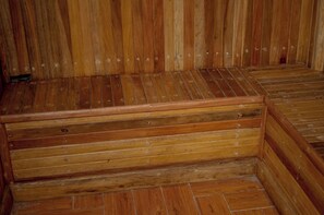 Uma sauna de madeira com piso inclinado e um banco de madeira.