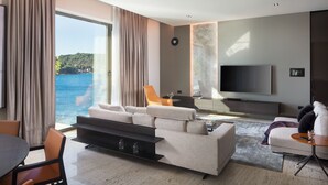A modern living room with a large TV, comfortable seating, a dining area, and a view of the sea. - New Villa, Comfort & Luxury, Beachfront, Prestigious Location, Full experience (Dubrovnik)