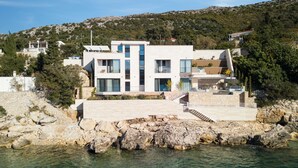 A modern coastal house with a stone facade, large windows, and a staircase leading to the entrance. - New Villa, Comfort & Luxury, Beachfront, Prestigious Location, Full experience (Dubrovnik)