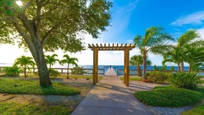 A pathway leading to a wooden pergola with a view of the sea. - Beach happy Geataway! (Ruskin)