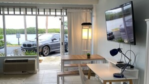 A hotel room with a bed, a desk with a computer, a TV, and a view of a parking lot with cars. - Beach happy Geataway! (Ruskin)