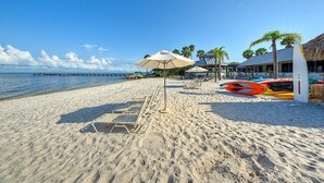 A beach with sun loungers, umbrellas, and kayaks. - Beach happy Geataway! (Ruskin)