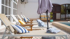 A poolside area with lounge chairs, towels, and umbrellas.