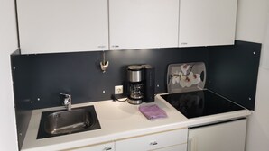 Eine kleine Küchenzeile mit Spüle, Kaffeemaschine, Toaster und Mikrowelle.