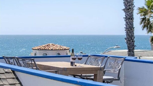 Une table avec deux verres à vin et une bouteille, donnant sur la mer.