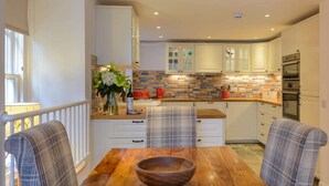 A modern kitchen with white cabinets, a wooden dining table, and plaid chairs.