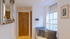 A hallway with a wooden door, a radiator, a bench with cushions, and a window with a view.