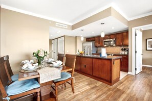 Una cocina moderna con armarios de madera, una isla central y un comedor con una mesa preparada para cuatro.