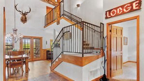 A spacious interior with a wooden staircase, a chandelier, and a sign reading "Lodge". - Newly Remodeled! Cedar Log Cabin with Gas Fireplace & Screened Porch (Branson)