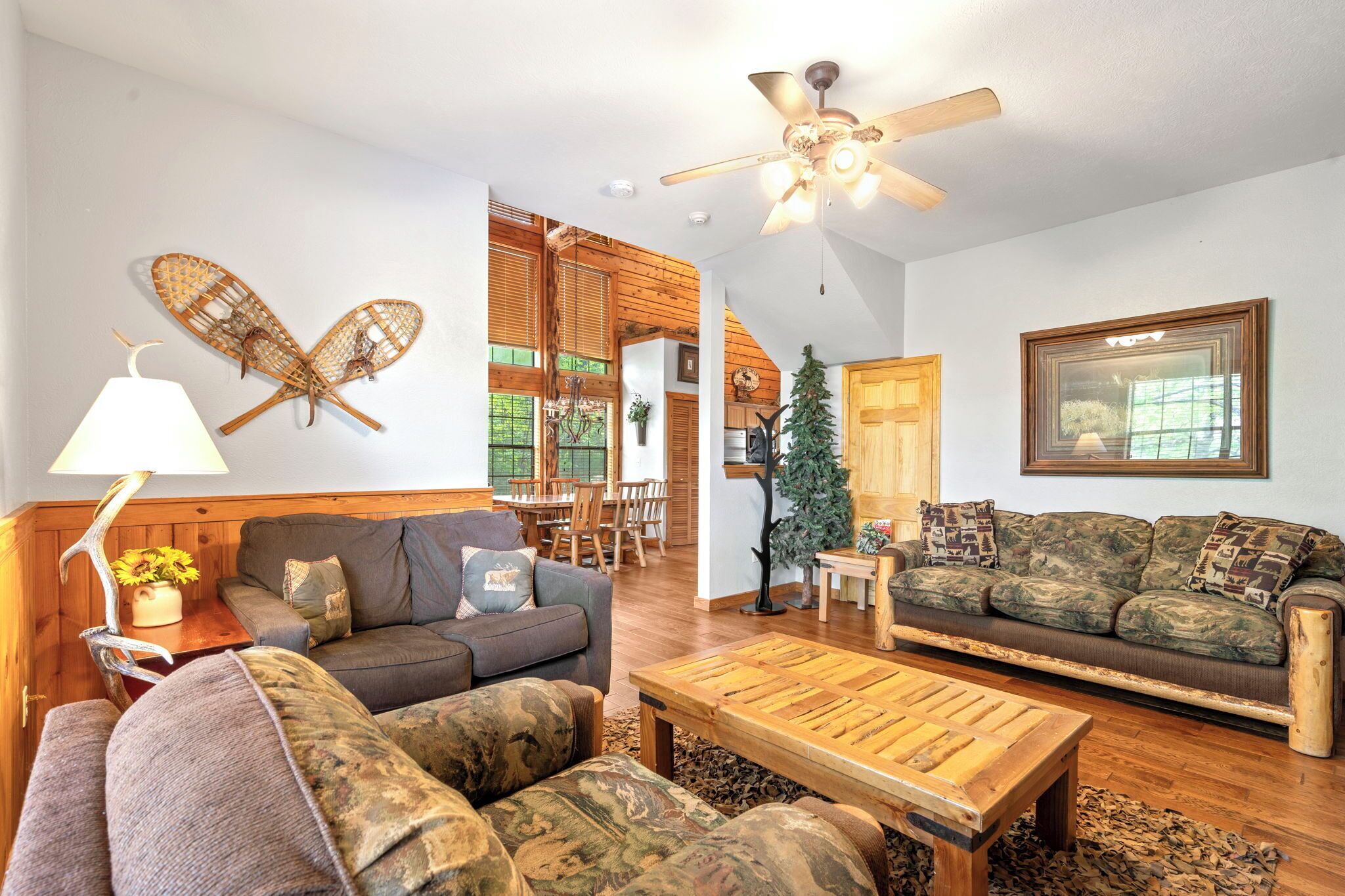 A living room with two sofas, a coffee table, a ceiling fan, and a wall-mounted lamp.