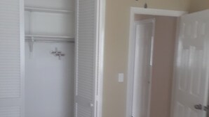 A bedroom with a ceiling fan, a bed, and a closet with sliding doors.