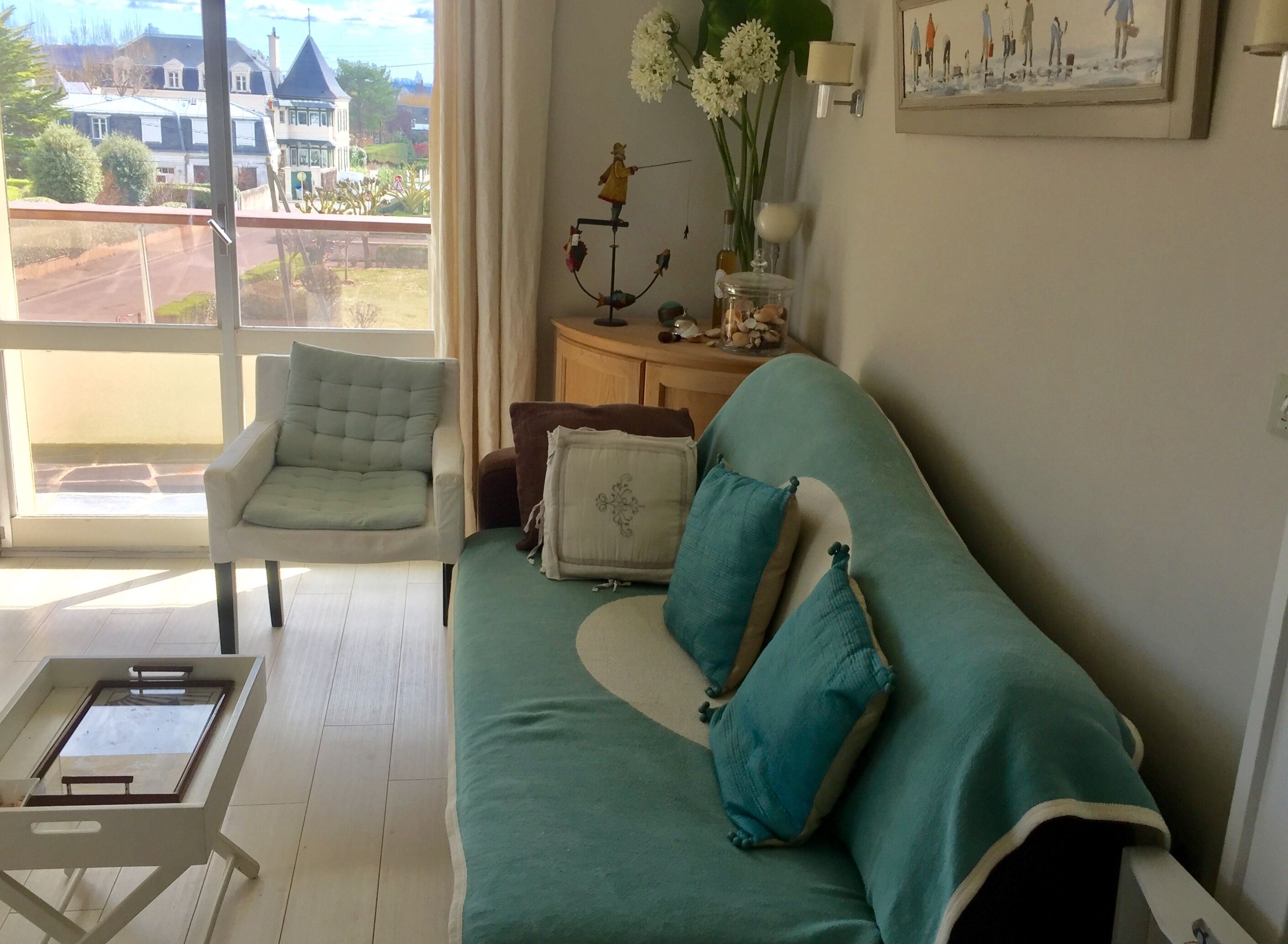 A living room with a sofa, a chair, a small table, and a view of the outside.