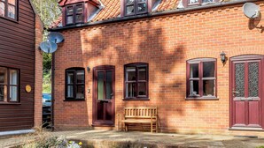 A brick house with a sloped roof, multiple windows, and a wooden bench outside. - A stylish getaway for discerning guests looking for a great coastal break. (Cromer)